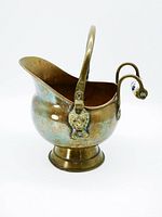 Left side view of vintage copper coal scuttle bucket showing lion head handle and spout