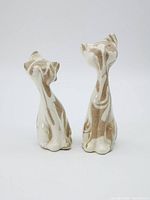 Two ceramic cat figurines showing back and side profiles, displaying marbled ash swirl pattern and glossy finish.