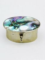 Closed oval pill box showing the Abalone shell inlay on the hinged lid with silver metal base.