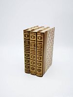 Front view of three vintage collector's edition Shakespeare books showing spine titles and decorative embossed designs in gold on brown leather binds with patterned cloth sides.