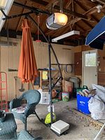 Photo showing the full cantilever umbrella setup with orange fabric, black coated metal frame, and weighted base with concrete blocks.