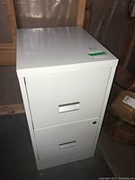 Front view showing two drawers, white metal cabinet with handles and lock hole.