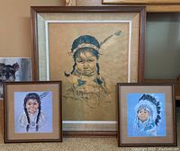 Three framed Indigenous-themed artworks by artist Oxborough displayed together on carpeted floor in front of wooden furniture. Showing size and relative dimensions.
