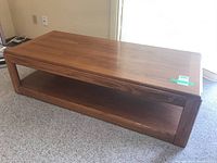 Front view showing the rectangular oak wood coffee table with a lower shelf and the wood grain finish.