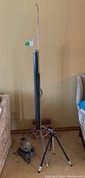 Photo of Aurora roll-up projection screen in black metal case with hanging hook and carrying handle, along with Pixur tripod and Skan 200 projector on floor