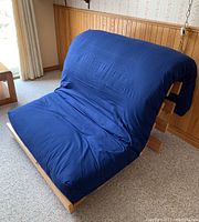 Side view of single futon chair with blue mattress cover in seating position