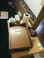 Wide view of desk tray with stacked items including notebooks, dot matrix paper, paper roll, tape dispenser, pens, crayons.