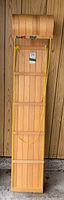 Front view of wooden toboggan leaning against wood panel wall.