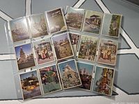 Overview of 18 vintage Disneyland collectible cards arranged in plastic sleeves, showing various attractions and Disney characters.