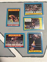 Front view of five WWF 1987 WrestleMania III trading cards showing wrestling moves and titled scenes.