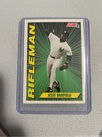 Front view of a 1991 Score Jesse Barfield Rifleman baseball card with Barfield pitching, in protective plastic case.