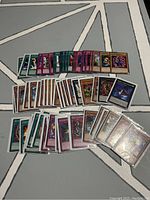Photo showing 70 Yu-Gi-Oh! cards including monster, spell, and trap cards arranged in rows on a gray and white patterned surface.
