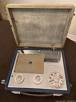 Opened view of the Pye Jewel Case portable vacuum tube radio showing speaker grille, control knobs, and tuning dial.