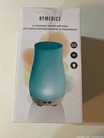 Front of the product box showing the diffuser image, HoMedics branding, and key features (glass, 6 hour runtime, light)