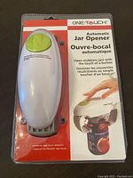 Front view of unopened packaging showing white and green automatic jar opener and branding.