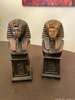 Front view showing both brass Egyptian style bookends with Pharaoh busts and bases with hieroglyphic symbols.