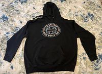 Front view of black Ed Sheeran Divide World Tour hoodie showing circular logo with car graphic and tour text.