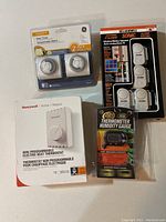 Lot overview showing Honeywell thermostat, GE basic timers, RadioShack alarm, and thermometer humidity gauge.