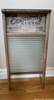 Front view of the wooden washboard with glass scrubbing surface and faded Economy Glass logo on top panel.