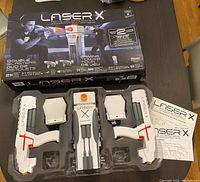 Laser X gaming set in original packaging showing two blaster guns, two sensors, interactive gaming tower and manuals.
