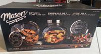 Front of the Mason Storage Jars box showing the three glass jars filled with various snacks, tilted design and metal lids.