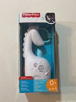 Front view of Fisher-Price Soothe & Go Giraffe baby soother in box, showing white giraffe shape with blue horn and tail, speaker grille and brand logo.