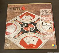 Front of closed Rustik Super Tock 4 game box showing design and key details including number of players 2-4 and age range 6 to infinity.