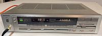 Front view showing tuner set to FM 88.5, power and speaker buttons, headphone jack engaged with plug.