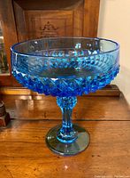 Side view of blue hobnail footed glass bowl, showing textured hobnail pattern and clear smooth top rim.