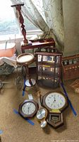 Full view of lot including wood shelves, clocks on floor, barometer, and plants stand near window