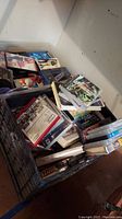 Bins containing assorted VHS tapes, DVDs, and PS3 games in varying condition with visible wear and stacking.