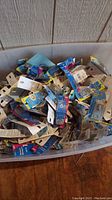 Large bin full of assorted hardware in original packaging including hasps, screws, hooks, and hangers