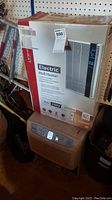 Photo of the Fahrenheat electric wall heater box and the LG dehumidifier below it showing front view of both items in storage area.