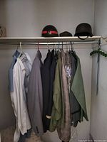 Closet rod with helmets on top shelf and assorted jackets and shirts hanging