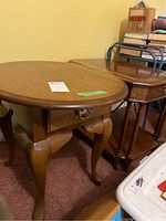 Photo showing two wooden side tables with curved legs and drawers, placed beside each other.