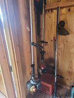 Four gas-powered weed trimmers stored in a wooden shed. Various shaft lengths and handle designs visible.