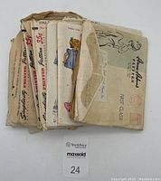 Photo showing 13 vintage sewing pattern envelopes stacked, some vintage wear and stamps visible.