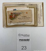 Stack of Victorian advertising trading cards featuring various businesses with floral artwork