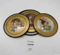 Three round vintage chimney covers with gold rims and Victorian women portraits under glass arranged together