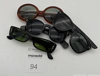 Four vintage sunglasses laid out on a white surface showing overall variety and condition.