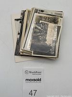 Stack of black and white photos and postcards showing the lot quantity and size