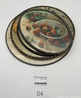 Top view of three stacked round fruit-themed decorative stove pipe covers showing metal rims and glass protection