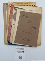 Stack of seven vintage cookbooks and booklets showing a variety of titles and cover conditions.