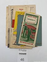 Stack of 7 folded vintage paper road maps with visible signage for Washington D.C. Sinclair map on top.
