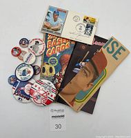 Overview of all items in the lot showing autographed envelopes, pinback buttons, book, guides, and flyers arranged on a white background.