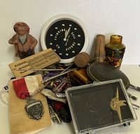 Assorted vintage small items arranged on table including timer, figurine, buttons, belt buckle parts, keys, crochet hooks, and small tools
