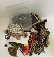 Top view of assorted small jewelry pieces, cuff links, chains, beads, brooches and pins in a mixed pile