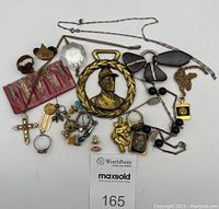 Overview image showing the assortment of jewelry and miscellaneous items including necklaces, pins, rings, pendants, miniature tools, and a crystal pendant.