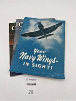 Three WWII Navy paper booklets with visible titles and Navy aircraft image on one cover.