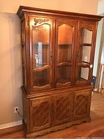 Full front view of wood china cabinet with three upper glass doors and four lower wood doors